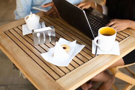 Black African American coworkers doing digital teamwork around a coffee cupの写真素材