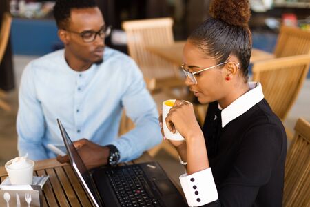 Black African American coworkers doing digital teamwork around a coffee cupの写真素材