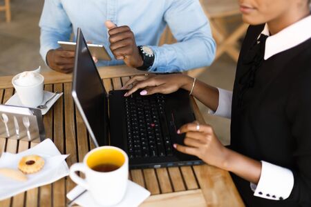 Black African American coworkers doing digital teamwork around a coffee cupの写真素材