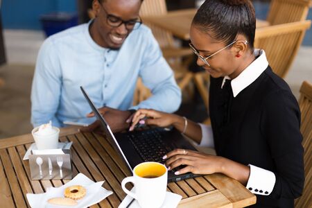 Black African American coworkers doing digital teamwork around a coffee cupの写真素材