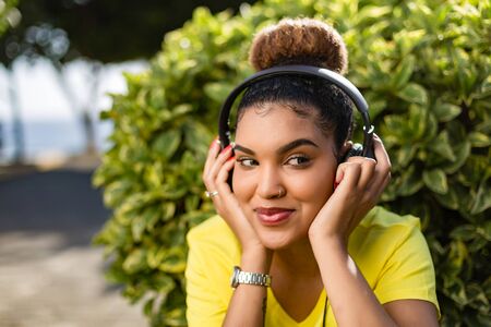 Pretty young black african american woman listening to music with a headphone outdoorの写真素材