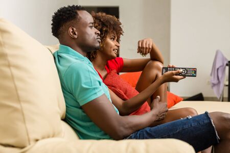 Black African American couple watching tv in the living roomの写真素材