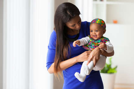 Young african american mother playing with her baby girlの写真素材