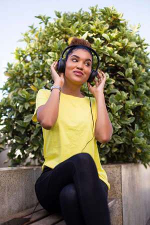 Pretty young black african american woman listening to music with a headphone outdoorの写真素材
