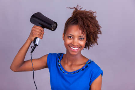 Young African American woman using an hair dryer on her afro hair - Black peopleの写真素材
