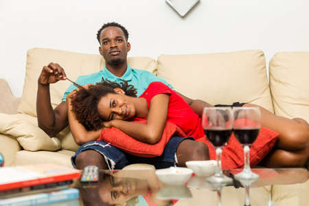 Black African American couple watching tv in the living roomの写真素材