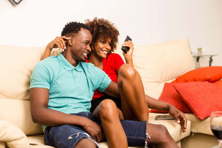 Black African American couple watching tv in the living roomの写真素材