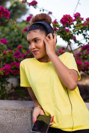 Pretty young black african american woman listening to music with a headphone outdoorの写真素材