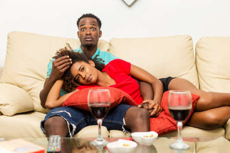 Black African American couple watching tv in the living roomの写真素材