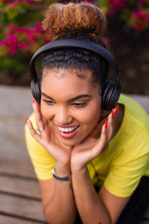 Pretty young black african american woman listening to music with a headphone outdoorの写真素材