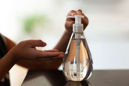 Black African American children hand using antibacterial antiseptic hand sanitizer gelの写真素材