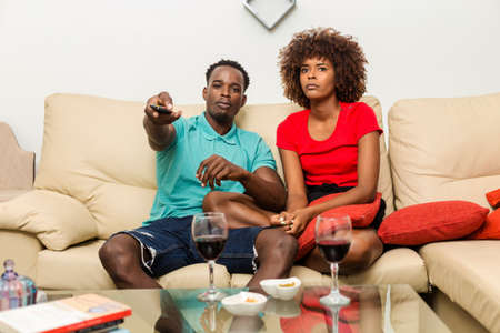 Black African American couple watching tv in the living roomの写真素材