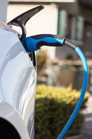 EV electric car pluged charging at a recharge station in the cityの写真素材