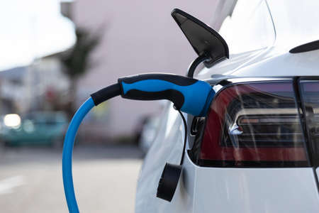 EV electric car pluged charging at a recharge station in the cityの写真素材