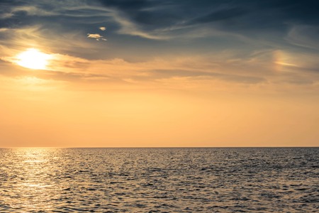 beautiful sky colorful sunset over the sea with a soft clouds and solar haloの写真素材