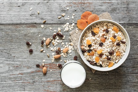 homemade muesli with dried fruits and milk on rustic wooden background. top view. healthy breakfast
