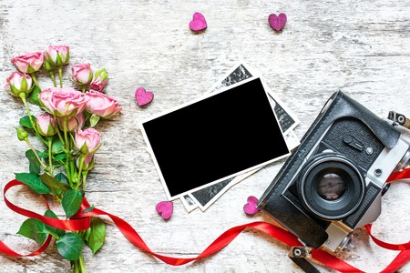 vintage retro camera and blank photo frame with flowers on valentines day background. top view