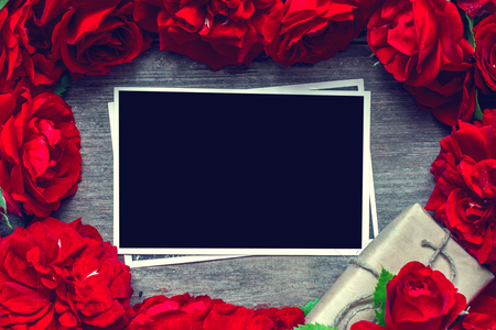 blank photo card in frame made of red roses flowers and gift box. mock up. flat lay. top view. valentines day background. vintage toningの写真素材