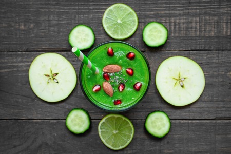 green healthy smoothie in a glass chia seeds, pomegranate and nuts with a straw over rustic wooden table. top view. detox drinkの写真素材