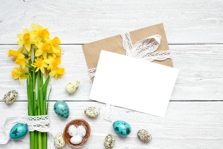 easter greeting card with easter eggs and spring flowers mock up over white wooden table. top view....