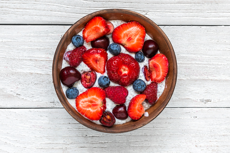 healthy berry yogurt or chia pudding with fresh raspberries, strawberries, cherry and blueberries in a bowl. healthy breakfast. top viewの写真素材