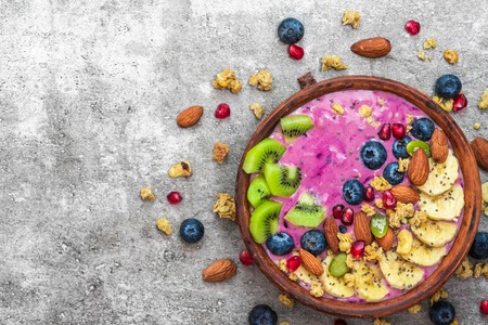 Healthy vegan breakfast. acai smoothie bowl with blueberry, fruits, granola, almonds, pumpkin and chia seeds. detox food concept. top viewの写真素材