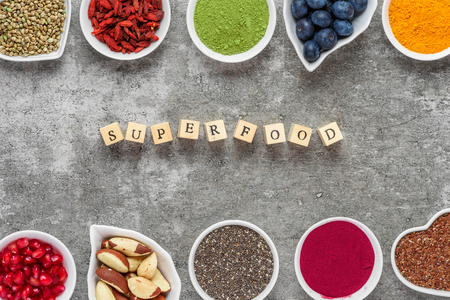 Superfood as acai powder, turmeric, matcha green tea, pumpkin and chia seeds, blueberry, goji berries, hemp and pomegranate seeds on dark concrete background. vegan food concept. top viewの写真素材