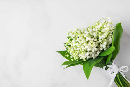 lily of the valley flowers bouquet on white marble background. flat lay. top view with copy space. wedding or holiday conceptの写真素材