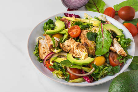 Healthy salad with grilled chicken breast, avocado, onion and tomato on white background. healthy diet food. close upの写真素材