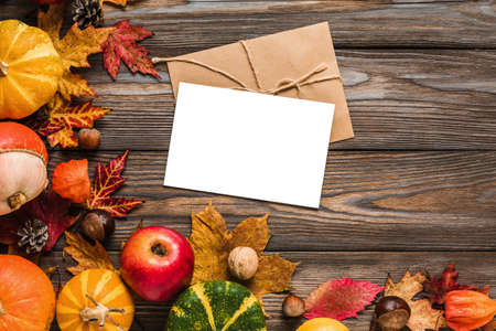 Thanksgiving, Halloween or autumn greeting card with pumpkins, apples, leaves, dry flowers and nuts on rustic wooden table. Flat lay, mock up. top view, copy spaceの写真素材