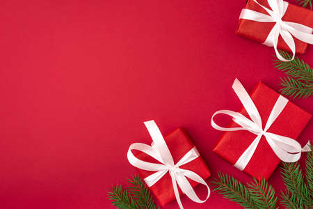 Christmas red gifts with white ribbon and fir tree on red background. top view. flat lay. Happy...