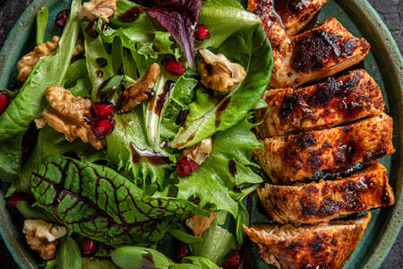 Fresh salad with grilled chicken fillet, mix greens, walnuts, pomegranate and balsamic sauce. close...