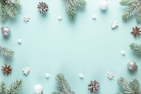 Christmas composition. Frame made of fir tree branches, holiday silver decorations on blue background. Flat lay. Top view with copy spaceの写真素材