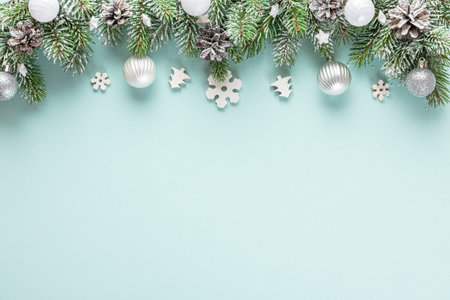 Christmas composition made of fir tree branches, holiday silver decorations on blue background. Flat lay. Top view with copy spaceの写真素材