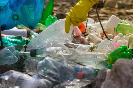 Close up of male collecting plastic garbage on the beach in trash bag. Earth day, Environmental protection, plastic pollution conceptの写真素材