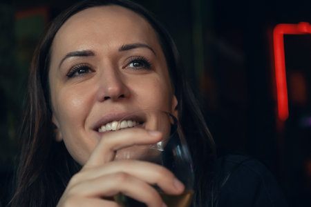 Portrait of attractive Caucasian smiling woman drinking glass of white wine in restaurant in the...
