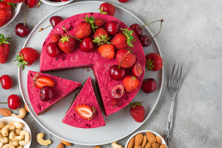 Sliced raw vegan strawberry and cherry cashews cake with fresh berries, nuts. Veggie dessert. Top viewの写真素材