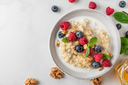 Healthy breakfast. Quinoa porridge with fresh berries, nuts and mint in a bowl on white background. top viewの写真素材