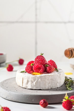 Camembert cheese with fresh berries, honey and thyme on white background. Healthy snack. Vertical orientationの写真素材