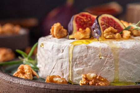 Camembert cheese with fig fruits, honey, walnuts and rosemary on dark background. French appetizer. Close upの写真素材