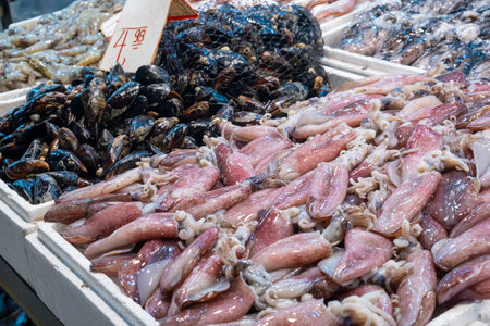 Fresh squids and mussels lying on ice counter at seafood market in Athens, Greece. Open shelf with...