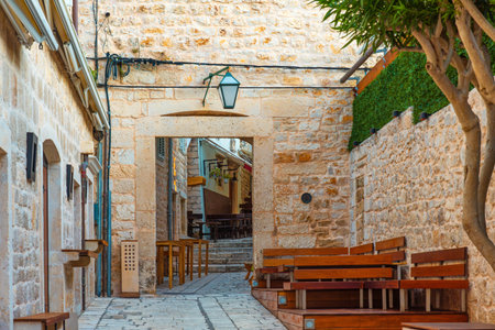 Old cozy street in the in medieval town Hvar with sidewalk cafe with nobody, Dalmatia, Croatia. Popular travel and tourist destination on summer vacationsの写真素材