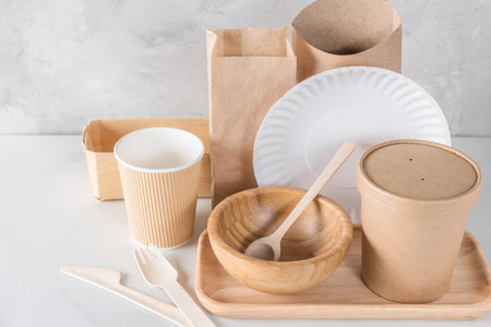 Eco-friendly, biodegradable disposable tableware and cutlery made of paper and wood. Cups, bags, cutlery and food containers for sustainable and environmentally conscious food service. Mock upの写真素材