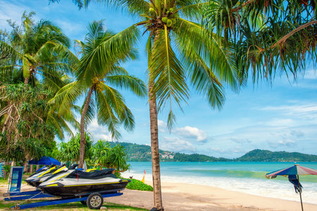 Patong beach with coconut palm trees and jet ski parked on the shore on Phuket island in Thailand with nobody. Tropical sandy beach, Thailand. Popular travel and touristic destination in Asiaの写真素材