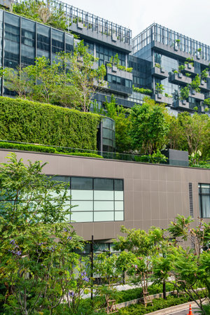 Building facade with green plants growth on the wall. Vertical garden in Bangkok city, Thailand. Eco friendly urban environment. Sustainable modern and ecological architecture. Vertical orientationの写真素材