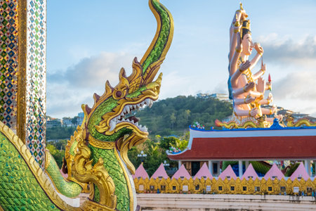 Close-up of green golden Naga serpent statue with the Guanyin sculpture, Buddhist Goddess of Mercy and Compassion with eighteen arms on background in Wat Plai Laem temple on Samui island in Thailandの写真素材