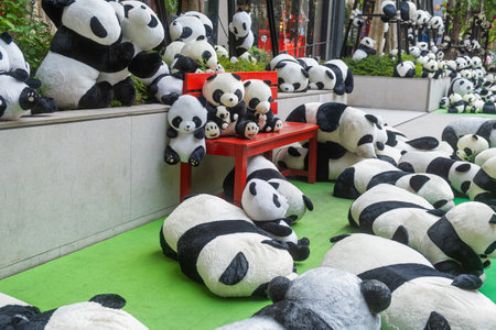 Outdoor display of numerous plush panda toys surrounding on green carpet in playful urban setting, Bangkok, Thailand. Public art installationの写真素材