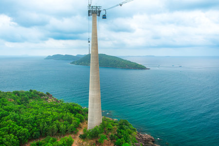Cable car support tower rising above tropical green island forest and turquoise sea. Longest Hon Thom cable car in the world on Phu Quoc island, Vietnam. Modern tourism technology and infrastructureの写真素材