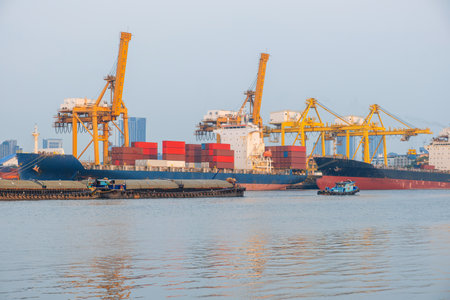Large cargo ships docked under towering yellow container cranes loading shipping containers with...