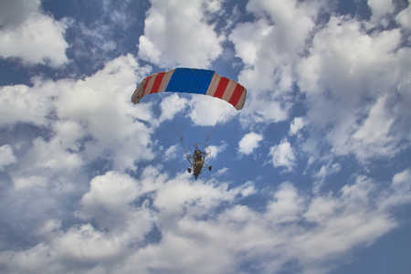 flying a motorized hang glider in a cloudy blue skyの写真素材